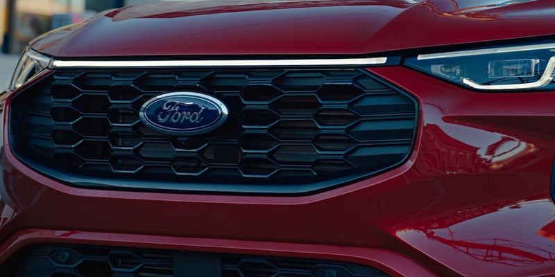 Close-up of a red Ford car's front grille with a black hexagonal pattern and blue Ford logo.